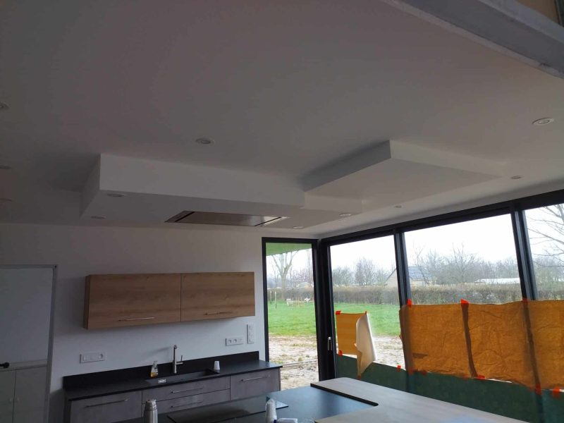 Plafond moderne dans une pièce de vie, avec jeux de volumes et finitions en plâtrerie.