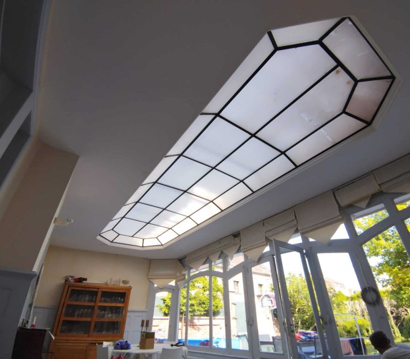 Plafond décoratif avec verrière de toit type atelier, apport de lumière naturelle et finitions soignées.