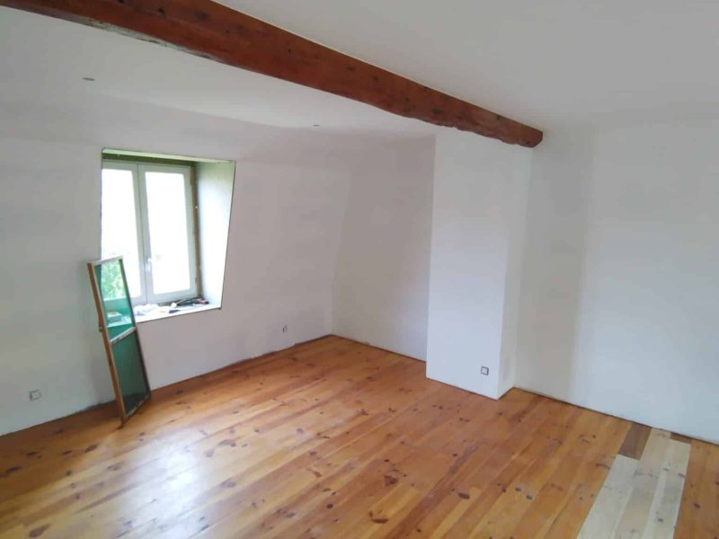 Agencement intérieur : pièce rénovée avec parquet bois, murs blancs et poutre apparente.