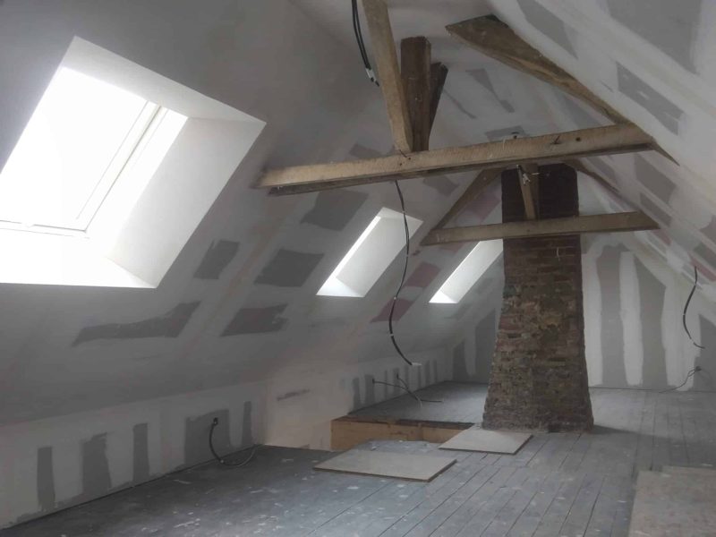 Isolation biosourcée dans des combles : rampants isolés et plaques de plâtre posées avec velux, prêt pour les finitions.