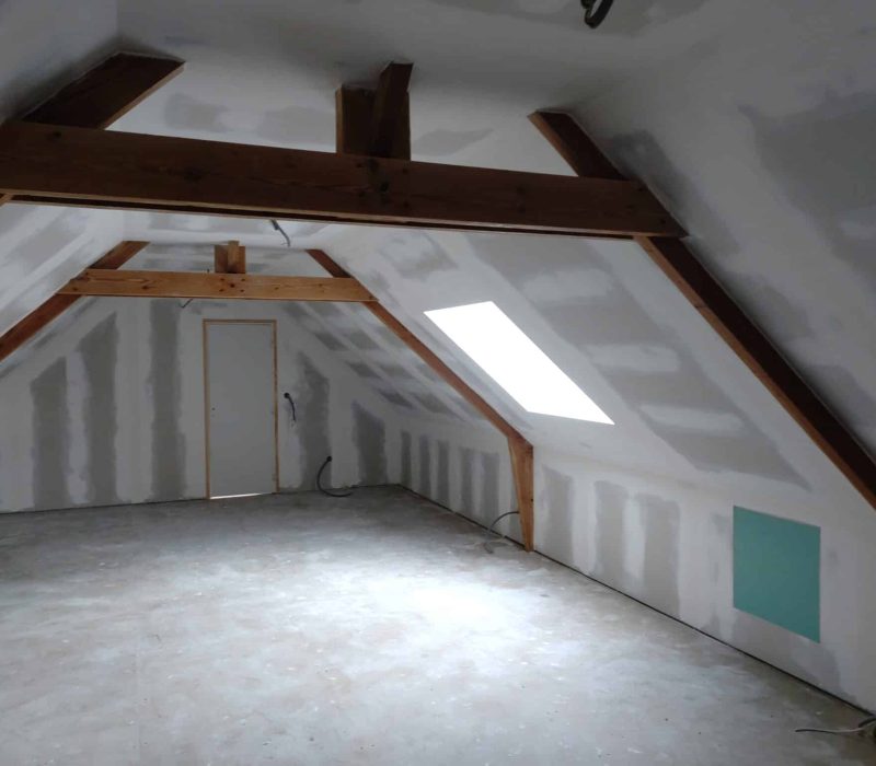 Isolation intérieure des combles aménagés avec plaques de plâtre posées et ouverture de toit (Velux) pour un futur espace confortable.