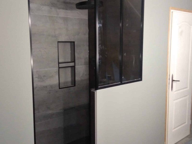 Agencement intérieur : verrière noire style atelier avec porte coulissante, douche et salle de bains moderne.